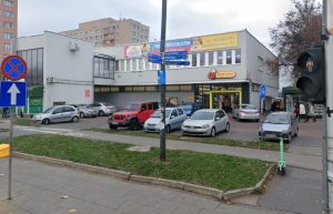 budynek w którym mieści się przedszkole nasze ananasy a przed nim parking i sklep spożywczy biedronka